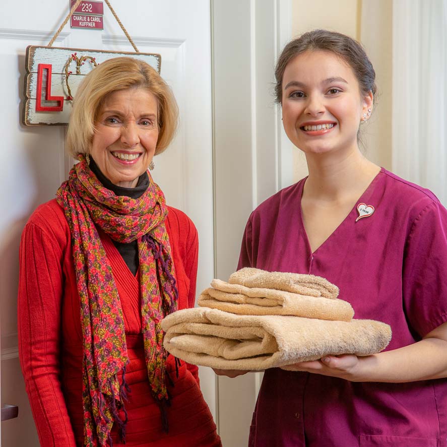 A team member delivering fresh linens to a resident at Cypress Springs